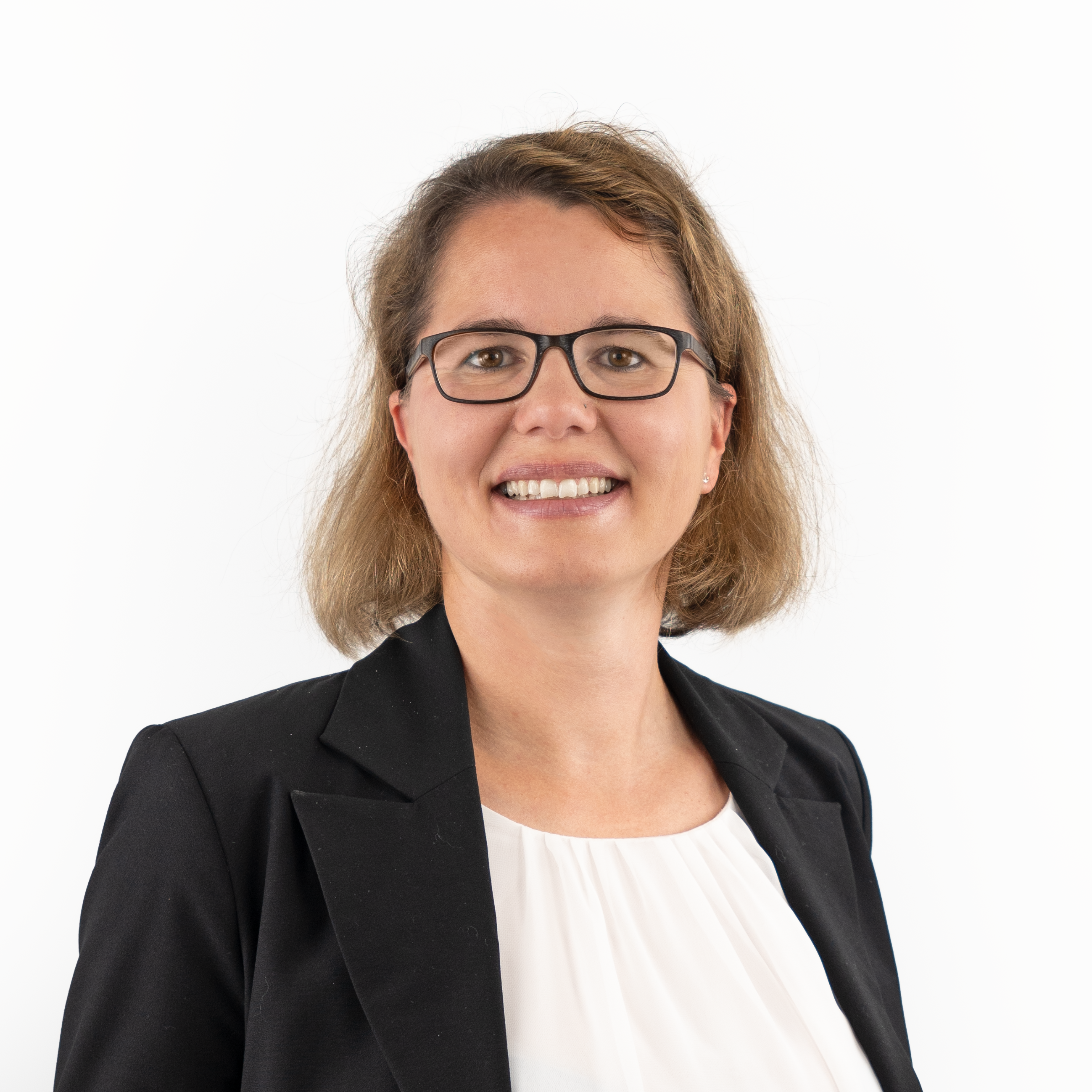 Porträt von Rechtsanwältin Katharina Benedikt. Sie hat schulterlange, braune Haare und trägt eine Brille. Sie lächelt und trägt einen schwarzen Blazer über einer weißen Bluse.